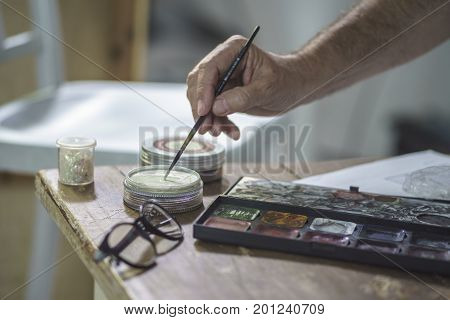 Some brushes and colors in a vintage Location ower a wooden table.