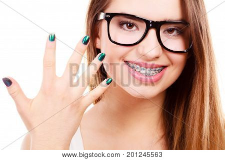 Vision and dentistry problems concept. Happy nerdy teenage wearing big eyeglasses showing her braces on teeth and painted nails.