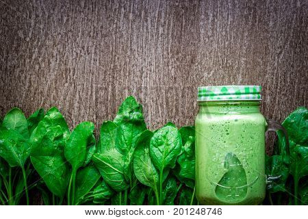 Glass of spinach juice on wooden background. Flat lay with place for text. Vegan and healthy food concept
