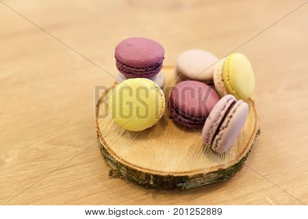 cooking, confectionery and baking concept - different macarons on wooden stand