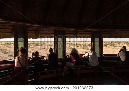ETOSHA NATIONAL PARK NAMIBIA - JUNE 26 2017: Unidentified tourists in the upper level of the hide at the waterhole at the Olifantsrus Rest Camp in the Etosha National Park