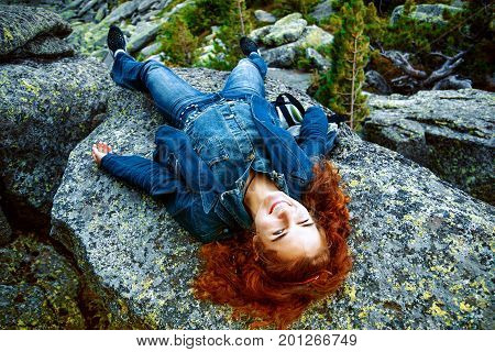 beautiful brunette girl in black clothes posing on a huge rock among stones