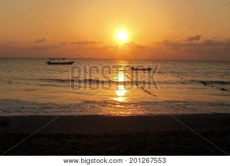 a orange sunset with small fishing boats