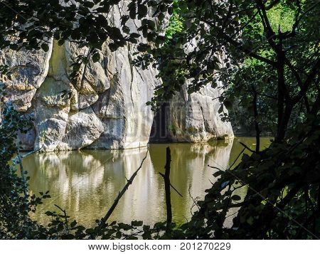 In the distance a cave in the Externsteine rock formation framed with the leaves and branches from the surrounding forest