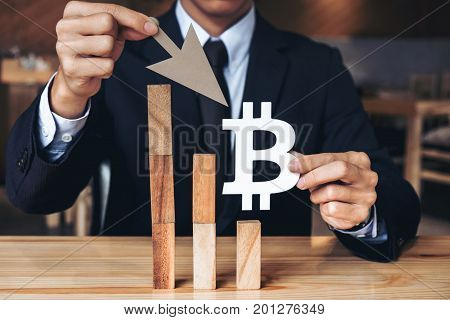 Business Economic crisis concept Businessman holding showing bitcoin symbol concede decrease of price and Depression of the economy. wooden block of the financial crisis of income in bitcoins.