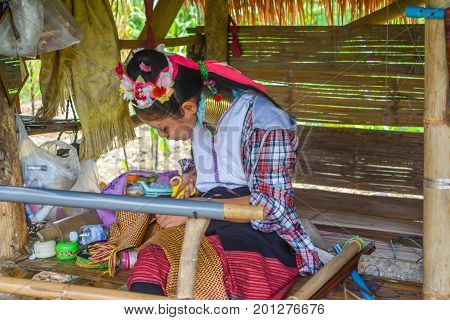 CHIANG MAI, THAILAND - July 10, 2017: Karen hill-tribe (Long Neck) woman weaving fabrics for a living at her house.
