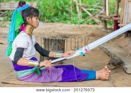 CHIANG MAI, THAILAND - July 10, 2017: Karen hill-tribe (Long Neck) woman weaving fabrics for a living at her house.