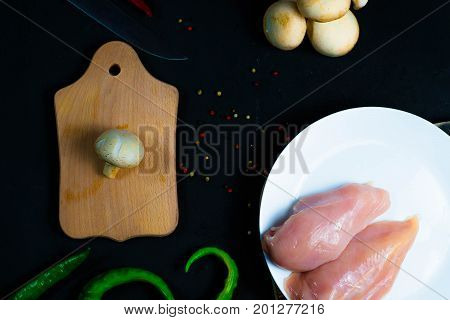 raw chicken wings with herbs in a transparent bowl Cauliflower with tomatoes and herbs and hot peppers with mushrooms on wooden background top view close up