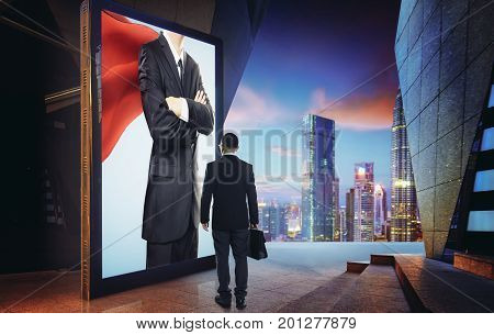 Young businessman looking the hero businessman on the advertising billboard screen . Successful businessman concept .