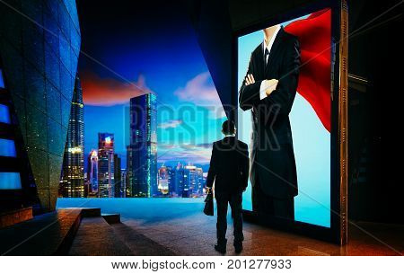 Young businessman looking the hero businessman on the advertising billboard screen . Successful businessman concept .