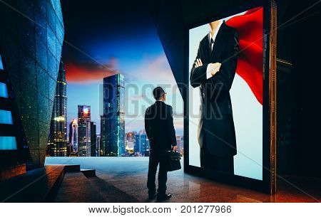 Young businessman looking the hero businessman on the advertising billboard screen . Successful businessman concept .