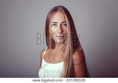 Portrait of calm pensive Caucasian blonde young beautiful girl woman model with long hair and blue eyes in white dress. Slav european model posing in studio on plain light background.