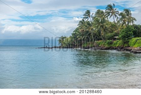A lone fisherman tries his luck on a beach in the Kahana area of Maui Hawaii.