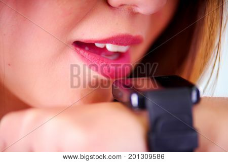 Close up of a young woman wearing in her wrist a smart watch with voice control, in a sunny day background.