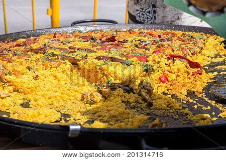 Public celebration or fest in Spain. Large fla frying pan with cooked paella. Selling to guests. Outdoors picnic lifestyle.