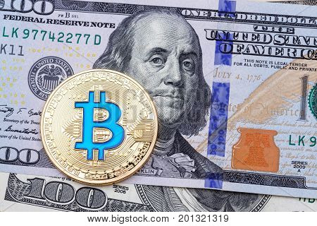 Close up of golden blue bitcoin on one hundred banknote. High resolution photo.