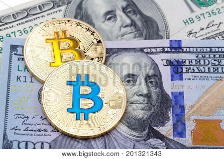 Closeup of golden yellow and blue bitcoin on hundred dollars banknote, macro shot. High resolution photo.