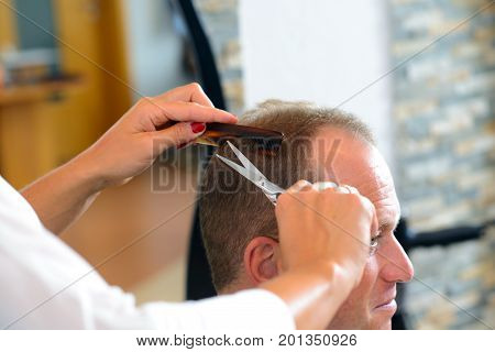 Female Hairdresser Cutting Hair Of Man
