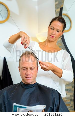 Female Hairdresser Cutting Hair Of Man