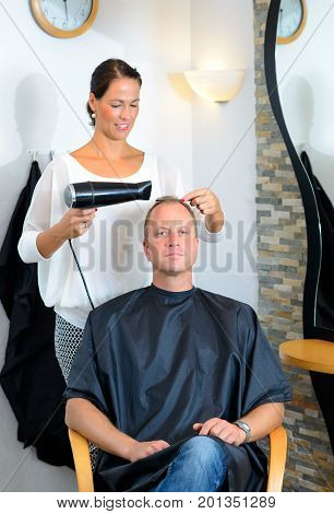 Female Hairdresser Cutting Hair Of Man
