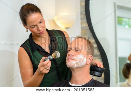 Female Hairdresser Shaving  Beard Of Man