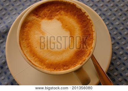 Cappuccino in white Cup on blue table flat lay