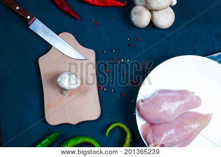 raw chicken wings with herbs in a transparent bowl Cauliflower with tomatoes and herbs and hot peppers with mushrooms on wooden background top view close up.
