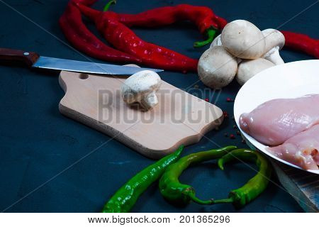 raw chicken wings with herbs in a transparent bowl Cauliflower with tomatoes and herbs and hot peppers with mushrooms on wooden background top view close up.
