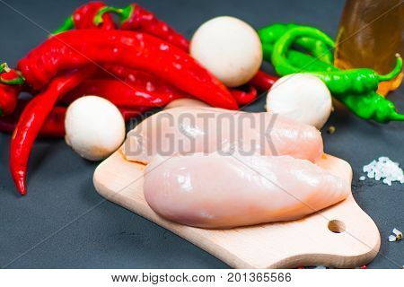 raw chicken wings with herbs in a transparent bowl Cauliflower with tomatoes and herbs and hot peppers with mushrooms on wooden background top view close up.