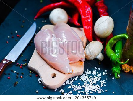 raw chicken wings with herbs in a transparent bowl Cauliflower with tomatoes and herbs and hot peppers with mushrooms on wooden background top view close up.