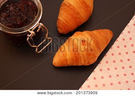 French Croissant with jam jar and napkin on black background