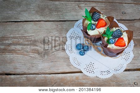 delicious sweet cupcakes decorated with cream chocolate cream cinnamon cocoa.decorated with fresh natural organic fruit cherry raspberry strawberry sugar mastic