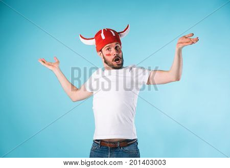 The football fan with megaphone over blue. The young man looking at camera with different emotions on face