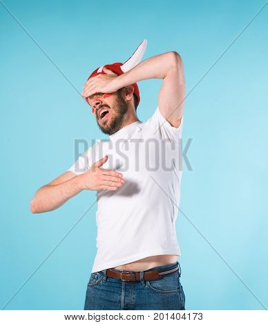 The football fan with megaphone over blue. The young man looking at camera with different emotions on face