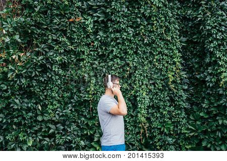 man stands in front of building in ivy and listins music concept