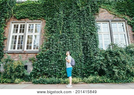 man listening music building in ivy on background summer day