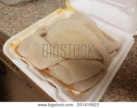 greasy ethiopian injera bread in a to go container