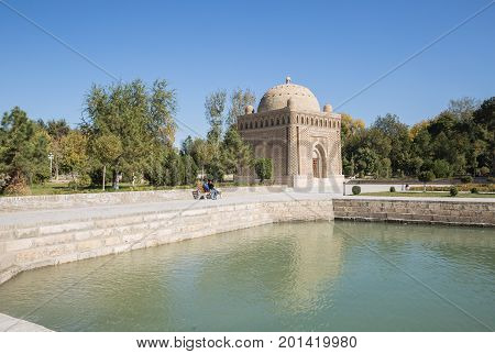 BUKHARA UZBEKISTAN - OCTOBER 19 2016: Unidentified people are sitting on a park bench near the Samanid mausoleum