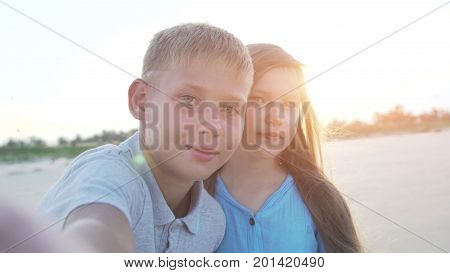 Little boy and girl of 8 - 10 years old making selfie using smartphone. Kids on vacation or holidays in summer.
