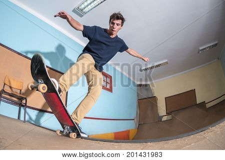 Skateboarder performing a blunt to fakie on a mini ramp at indoor skate park.