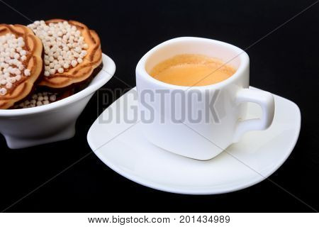Classic espresso in white cup with homemade cake on black background. Selective focus