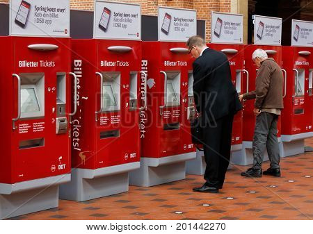 Copenhagen Denmark - August 24 2017: Two men buy tickets from ticket machines at the Copenhagen Central station.