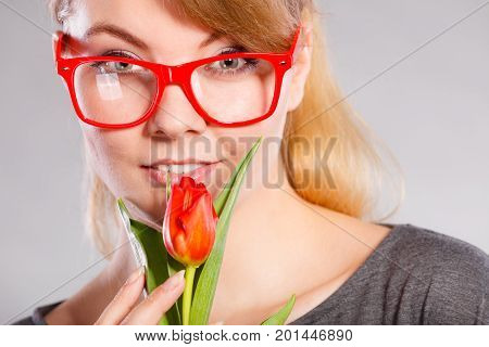 Delicacy and subtlety of women. Young adorable woman with spring flower. Portrait of beauty delicate girl in glasses with red beautiful tulip.