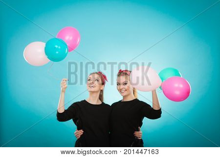Memory of childhood and forgotten dreams. Two cute lovely retro styled women behave like little girls. Adults trying to fly away by balloons to dream come true.