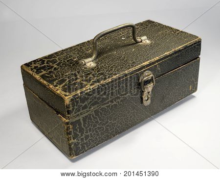 A wooden box with a metal handle and a latch on a light background. The box is painted with paint, the paint cracked with time. Retro.