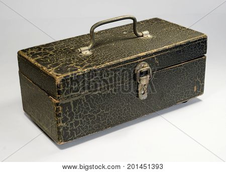 A wooden box with a metal handle and a latch on a light background. The box is painted with paint, the paint cracked with time. Retro.