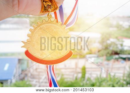 Winner hand holding golden medals to blur building background for show team success with their business Champion and Awards Concept