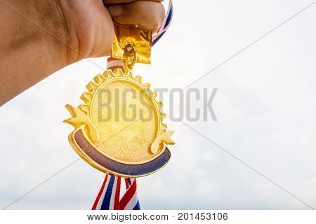 Winner hand holding golden medals to blur building background for show team success with their business Champion and Awards Concept