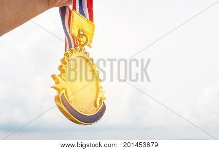Winner hand holding golden medals to blur building background for show team success with their business Champion and Awards Concept