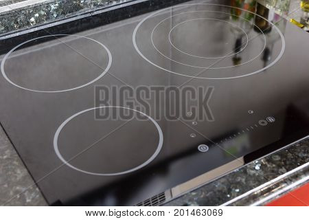 Modern black induction stove cooker hob or built in cooktop with ceramic top in white kitchen interior